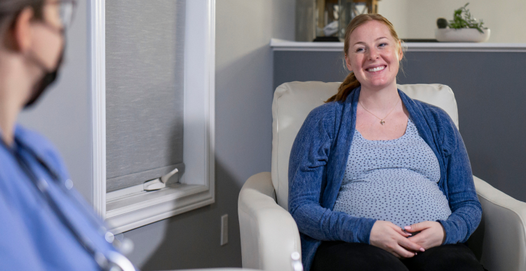 A pregnant woman smiling during an appointment with a medical professional