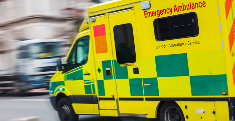 Photo of a speeding ambulance with a blurred background.