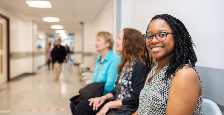 Woman sitting on a chair in a hospital corridor smiling to camera