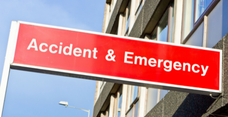 A thin, red, rectangular sign. The text, which is white, reads: Accident & Emergency. There is blue sky and a building in the background.