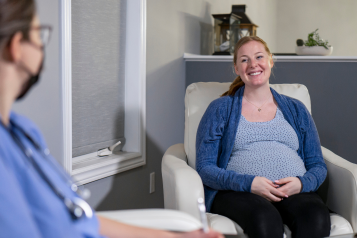 A pregnant woman smiling during an appointment with a medical professional