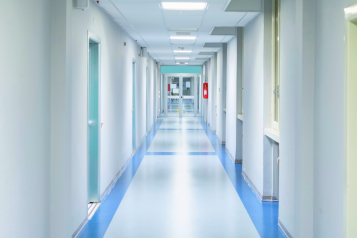 A blue and white hospital corridor with rooms off to each side.