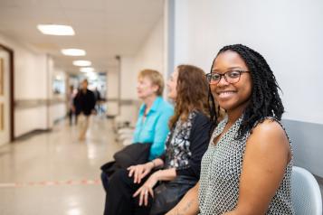 Woman sitting on a chair in a hospital corridor smiling to camera