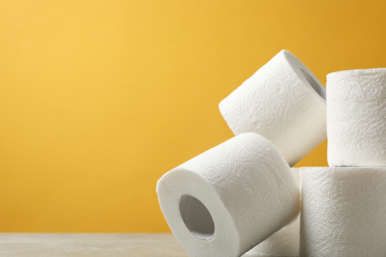 Four rolls of toilet paper stacked against a yellow background.