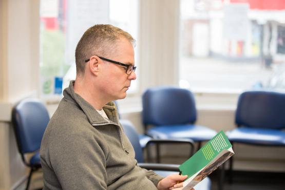 A man reading a leaflet in a waiting room