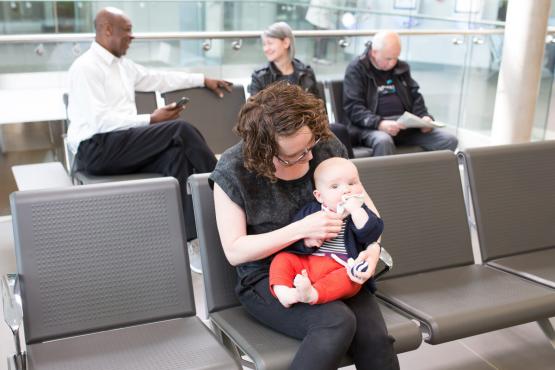 A woman sitting in a waiting room with a baby on her knee