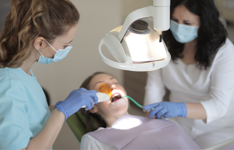 A patient lying on a dentists chair, receiving treatment from two dental professionals.