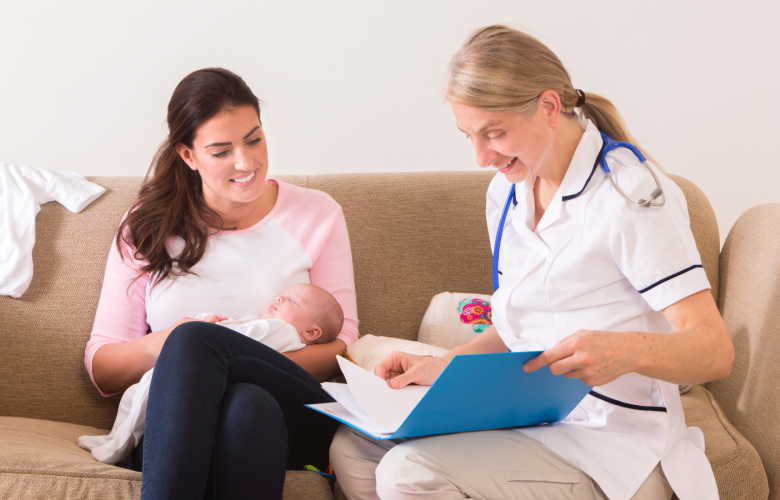 A mother holding a baby and a health visitor sitting on a sofa